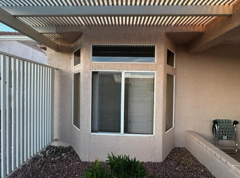 Sliding window screens cleaned under a louvered pergola in Peoria